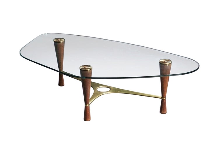 Asymmetrical rounded beveled top on three conoid legs joined by a curvilinear brass stretcher, small amount of wear to legs, flaking to glass around screw holes.
Measurements:57