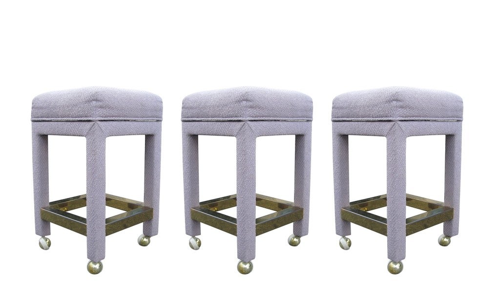 Set of three beautiful bar stools upholstered in a lavender cotton blend fabric and brass footrests,

These stools are very substantial, the legs and brass pieces are very thick and heavy, they have the Milo Baughman Paul Evans flair but there are