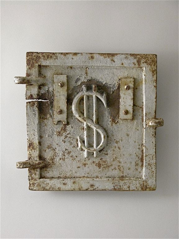 A small furnace door made of cast iron, humorously embellished with a relief image of the dollar sign.