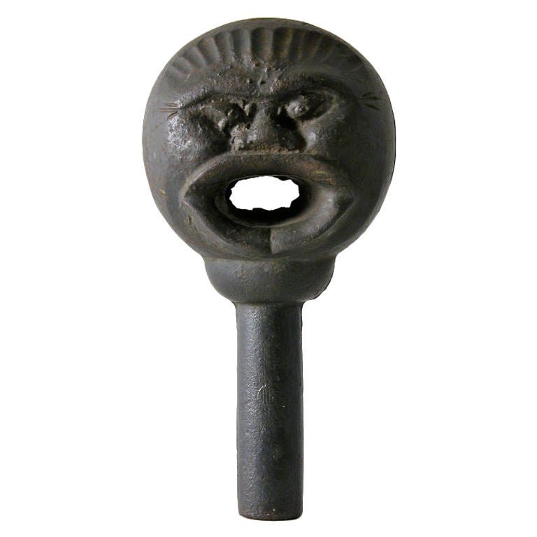 An iron pole finial in the form of a face for the purpose of hitching horses