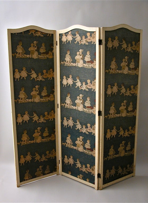A three part lacquered wood folding screen framing block printed textiles nursery in theme.