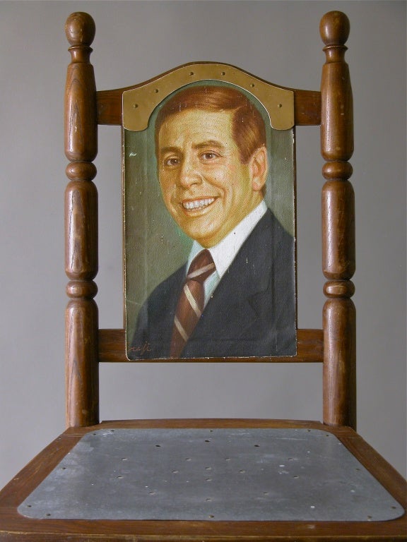 A turned wooden chair with metal seat and wired legs becomes a humorous display of portrait / sitter.