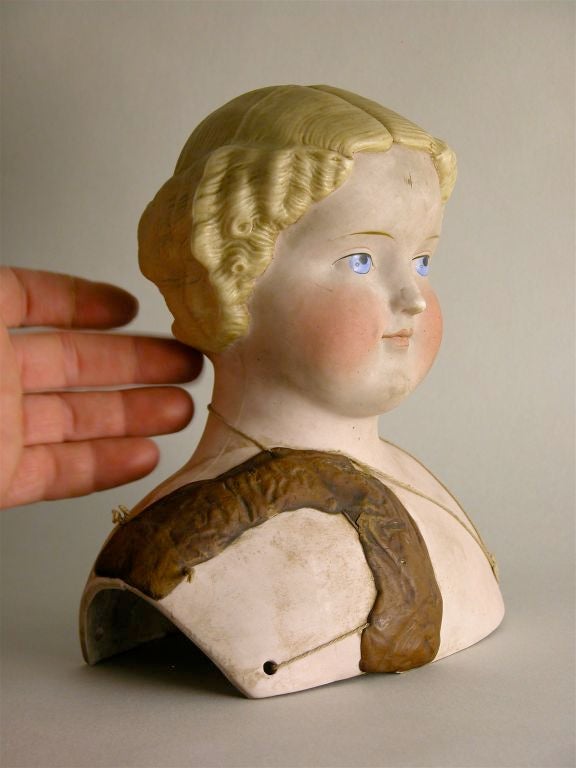 A china painted ceramic doll bust with mend of putty and string.