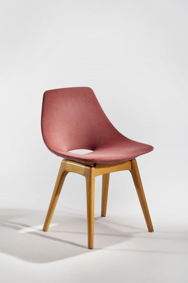 Molded plywood chairs upholstered in a textured pink fabric with wooden base.

About the designer: Pierre Guariche (1926-1995) attended the ENSAD (École Nationale Supérieure des Arts Décoratifs de Paris) where he studied under René Gabriel. He