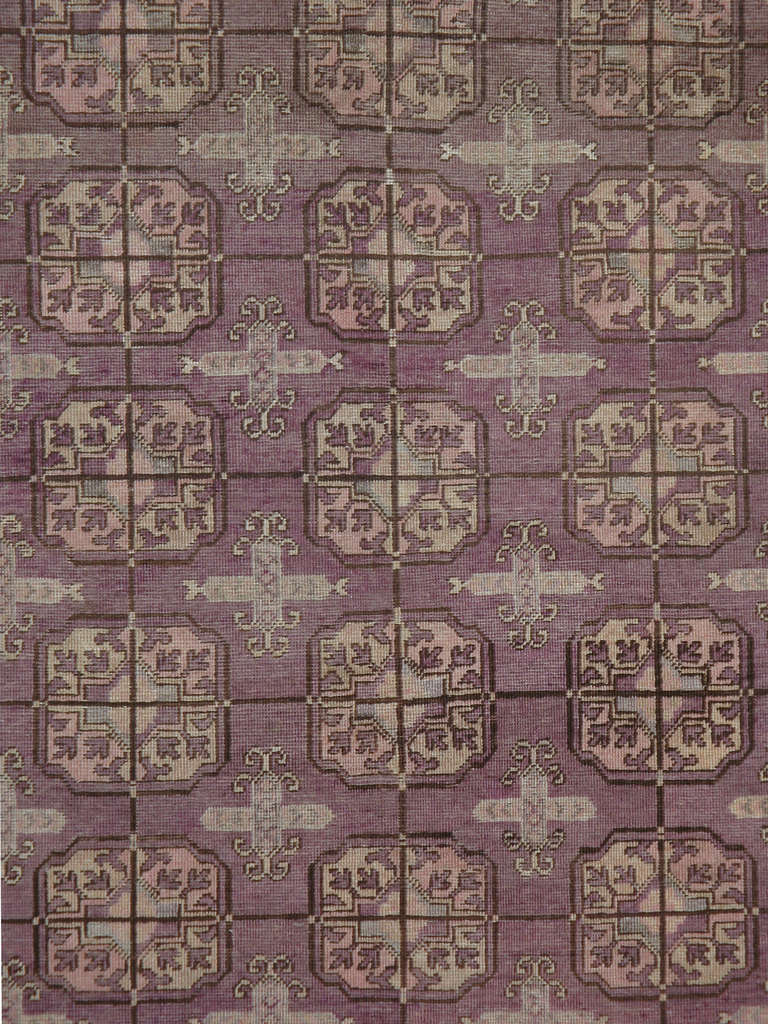 Tapis Khotan classique du début du XXe siècle du Turkestan oriental, présentant des rosettes encadrées disposées en rangées sur un fond aubergine.
Les tapis et moquettes anciens de Khotan étaient produits dans la ville oasis du Turkestan oriental,