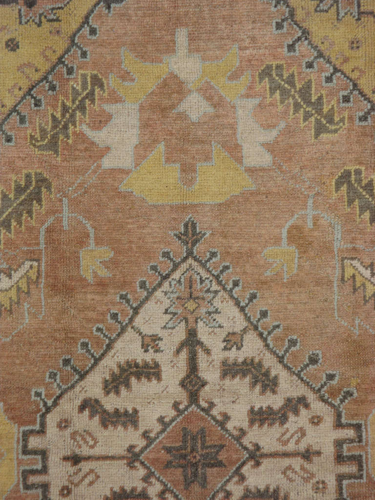 A classic early 20th century Turkish Oushak carpet with a central medallion set on a light copper ground, accents of green and yellow.