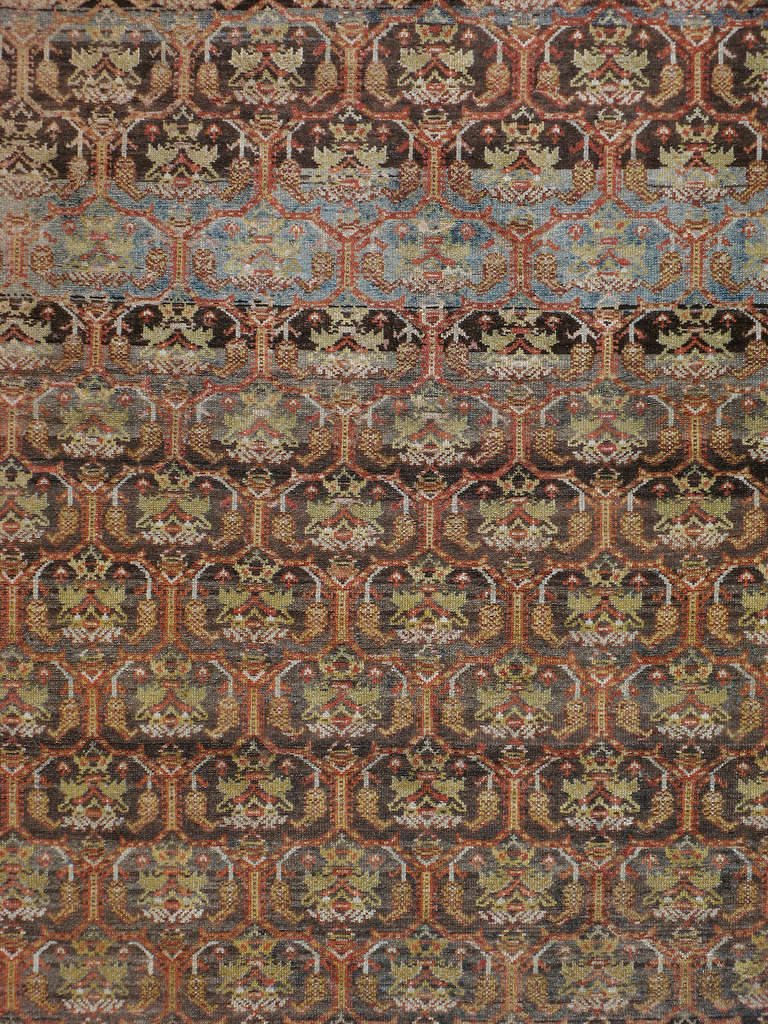 Ein persischer Malayer-Teppich aus dem ersten Viertel des 20. Jahrhunderts.  Eine Palette von Rost-, Grün- und Blautönen bildet die großformatige Bordüre und das symmetrische Allover-Muster.