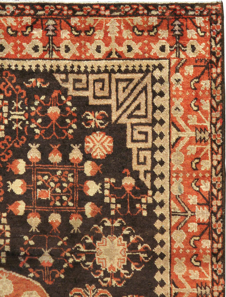 A first quarter of the 20th century East Turkestan carpet with a medallion consisting 14 pomegranate designs and a field with multiple cloud motifs.