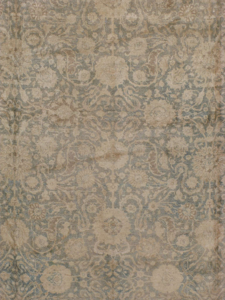 Dies ist ein klassisches persisches Täbris aus dem frühen 20.  Ein Allover-Teppich aus Täbris, blühende Blumen und Weinranken umrahmen den blau-grauen Grund.  
Seit dem 17. Jahrhundert exportiert der Iran kunsthandwerklich gefertigte Teppiche in