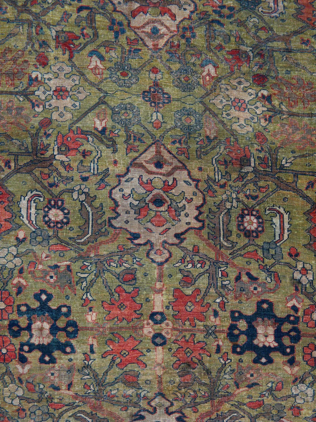 An antique distressed Persian Sultanabad carpet from the turn of the 20th century in shades of olive green and rust red.