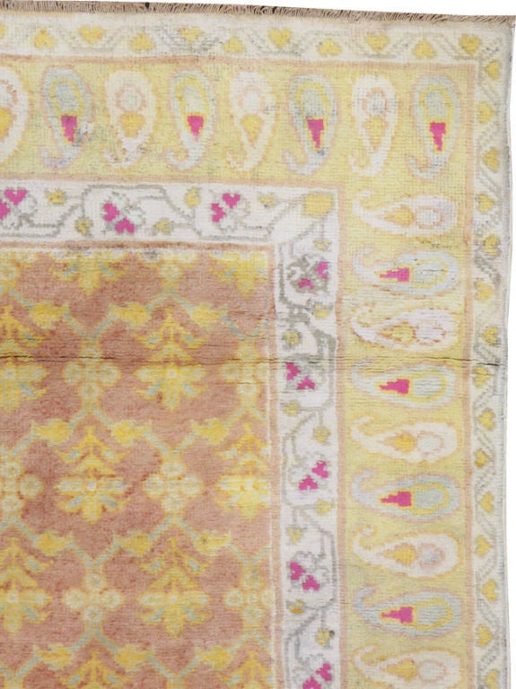 Un Agra de algodón indio de mediados del siglo XX.  Una alfombra Agra de algodón, de fondo ciniamon encerrado por un borde amarillo de estilo paisley.