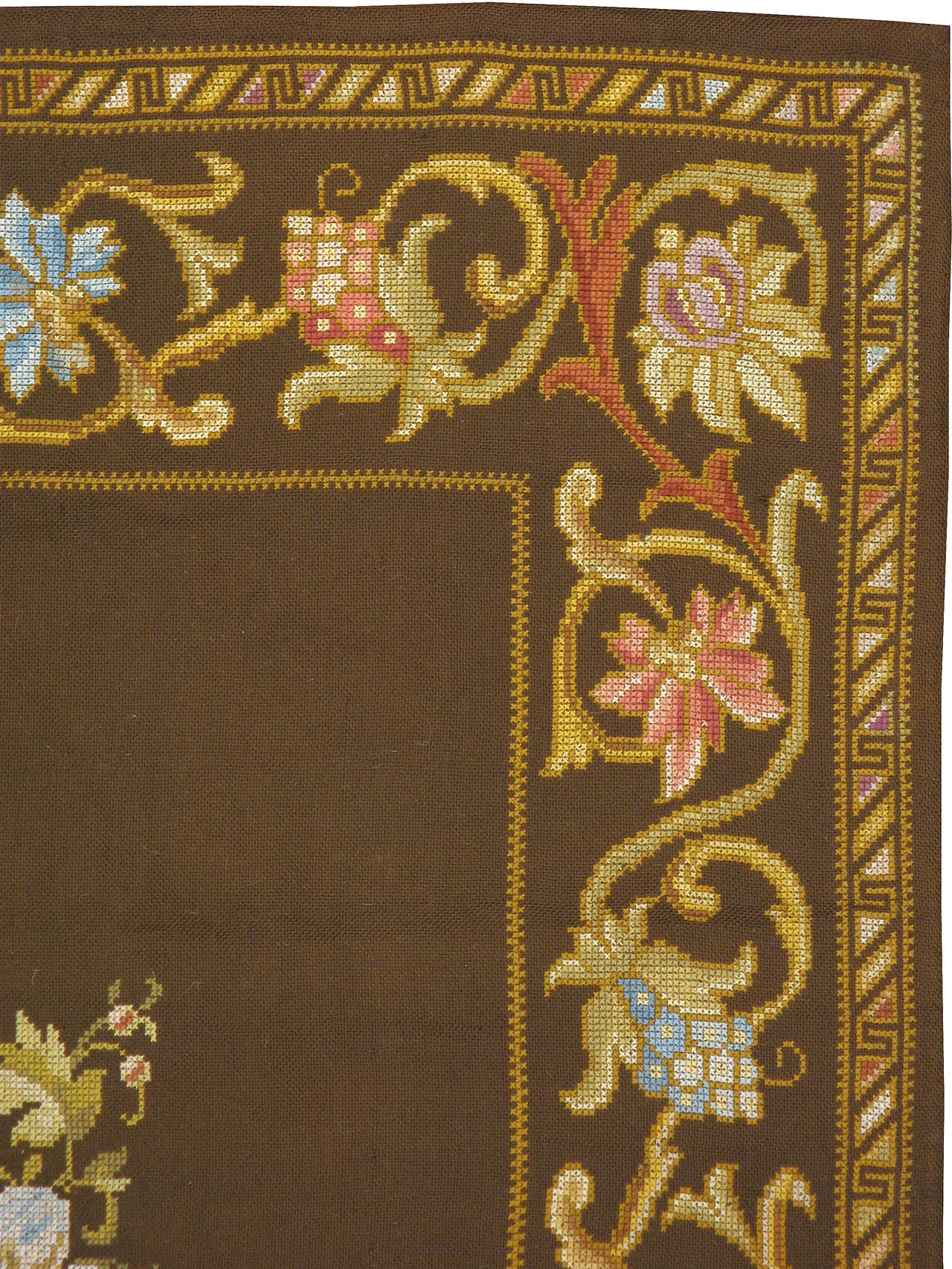 An antique Ukrainian needlepoint carpet from the second quarter of the 20th century. A medallion of elegant floral blossoms sits atop a brown minimalistic background confined by a graceful vine and scroll border.