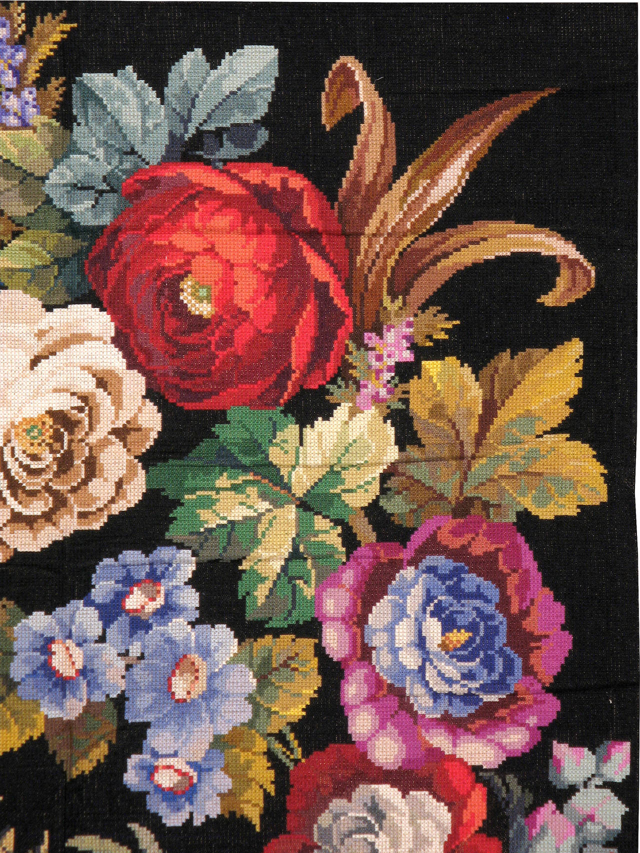A vintage Portuguese needlepoint carpet from the third quarter of the 20th century with a large, lifelike floral motif over a black background.