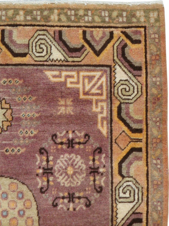 Alfombra Khotan, medallón central con hojas rodeadas de frutos granados sobre un campo berenjena.