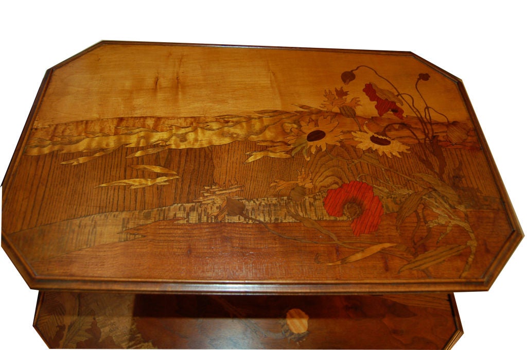 A two tiered French Art Deco table made of walnut with exotic wood inlaid in floral designs. Signed in marquetry Galle.