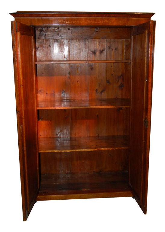 Biedermeier Armoire- veneer of walnut, fruitwood and ebonized wood. Rectangular step molded top, flanked by ornamental intarsia pilaster, ebonized circular columns above inlaid pilaster, 2 long doors w/root wood inlay, shelved, raised on square feet.