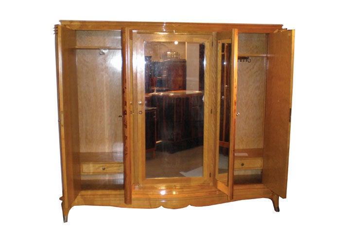 French Art Deco armoire - sycamore with inlaid mother of pearl and marquetry. Four exterior doors with interior shelves. Two center doors are mirrored on inside with an interior set of mirrored doors opening to interior drawers and shelves. France
