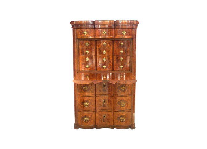 Secretaire Biedermeier de nogal y madera de raíz con herrajes de latón.  Superficie de escritura frontal en caída con cajones interiores sobre tres grandes cajones exteriores.