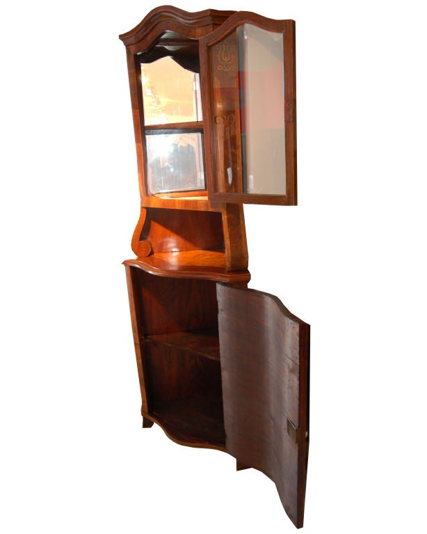 Neo-Baroque corner display cabinet made of walnut and root wood with ebony inlay. Top vitrine has one interior shelf and bottom cabinet has one interior shelf.