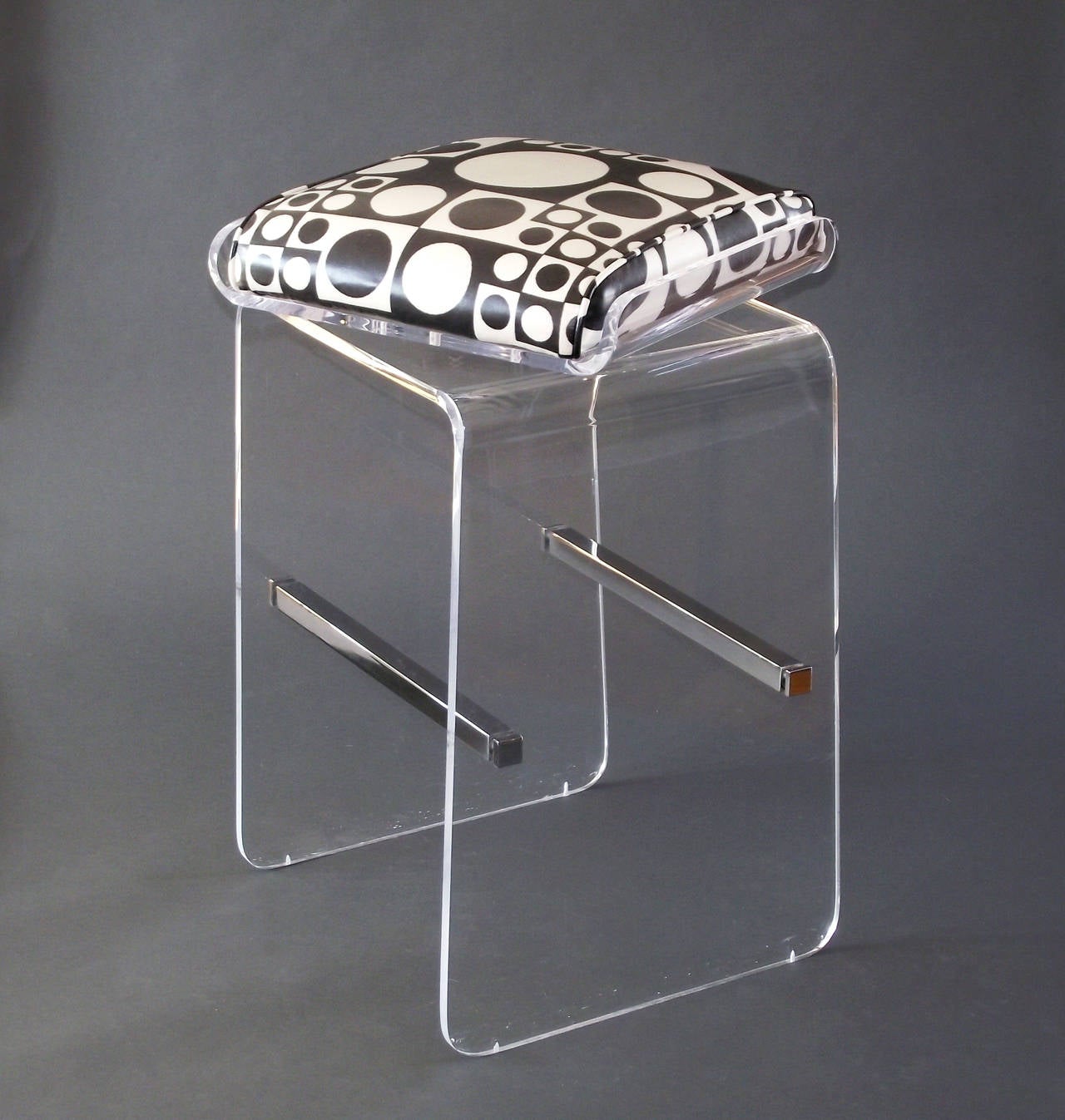 A matching pair of waterfall barstools in lucite with chrome cross stretchers and end caps, upholstered in a graphic op-art vinyl fabric, designed by Charles Hollis Jones. The seats swivel a full 360 degrees and do so smoothly. *Please note: the