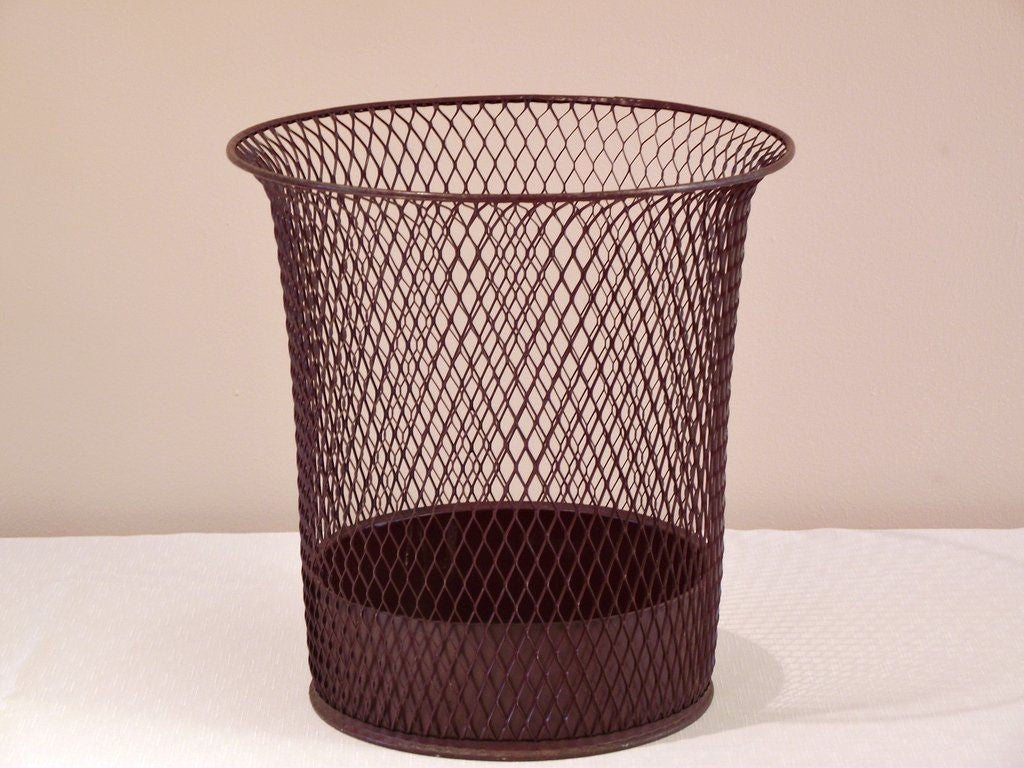 A mesh, sheet metal wastepaper basket with an enclosed bottom, a flared rim and rolled metal lip and base by Nemco (Northwestern Expanded Metal Company of Chicago), manufactured by the F.H. Lawson Company. In its original bittersweet chocolate paint