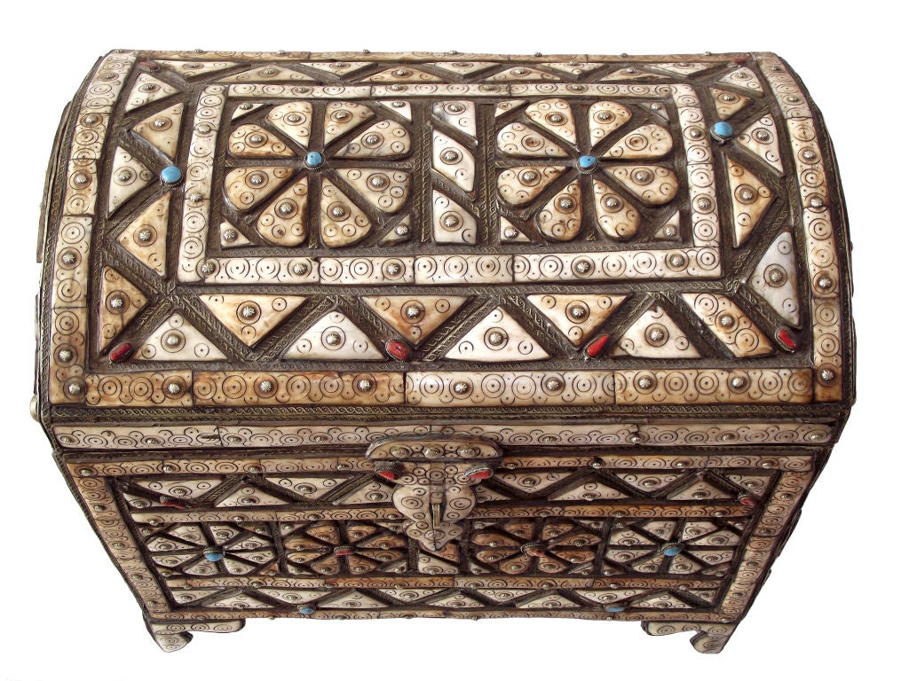 A highly-decorative, handcrafted Moroccan 'treasure' chest made of hardwood and adorned with a mosaic design of camel bone, studded throughout with turquoise, coral stone and silver metal rosettes and trimmed/outlined in decorated metal. The
