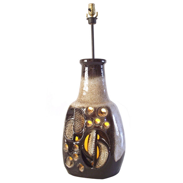 A huge, Ruscha glazed pottery lamp in shades varying from cream to dark chocolate brown with intriguing geometric cut-out sections to the front, creating an incredible, illuminated ceramic sculpture when the bulb inside the base is lit. The lamp's