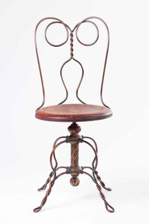 A highly lyrical, swiveling desk or task chair with a solid, wrought copper frame and solid mahogany seat, manufactured by Tonk Mfg. of Chicago circa late 18th/early 19th century. The sinuous backrest is complemented by four braided legs and a