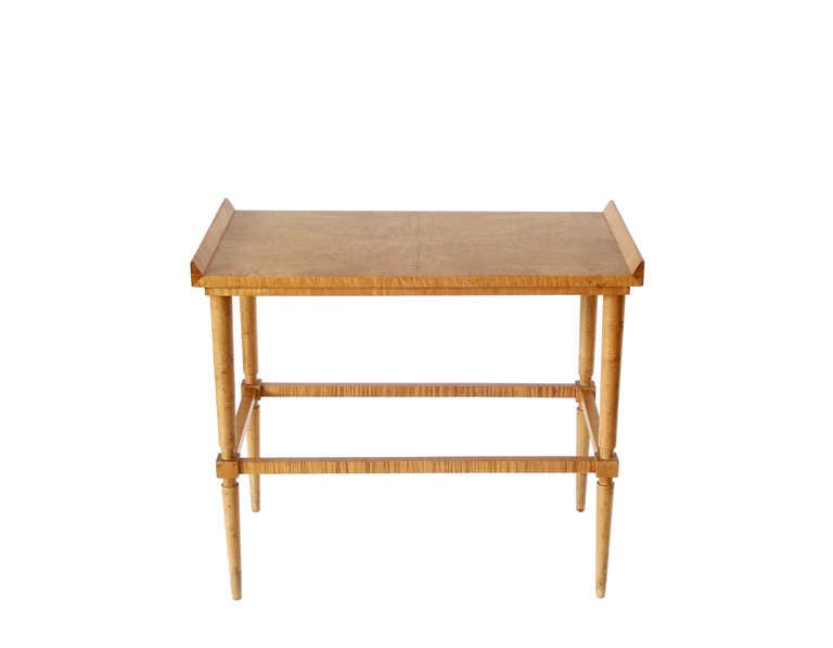 Beautiful studio craft table, executed in solid and veneered birdseye maple with a matte finish that comprises a bookmatched top with raised ends and a stepped, double apron supported by turned, tapering legs intersected by box stretchers. Striking