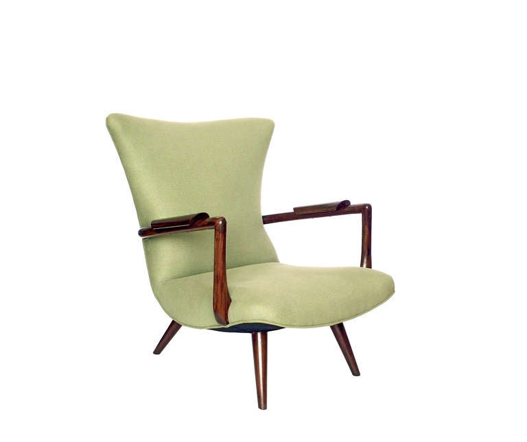 A low-profile, Mid Century lounge chair with solid wood arms and legs finished in a rich espresso stain and upholstered in a subtly textured, pistachio-colored cotton. The curved seat and backrest create a dynamic silhouette and though we are unsure