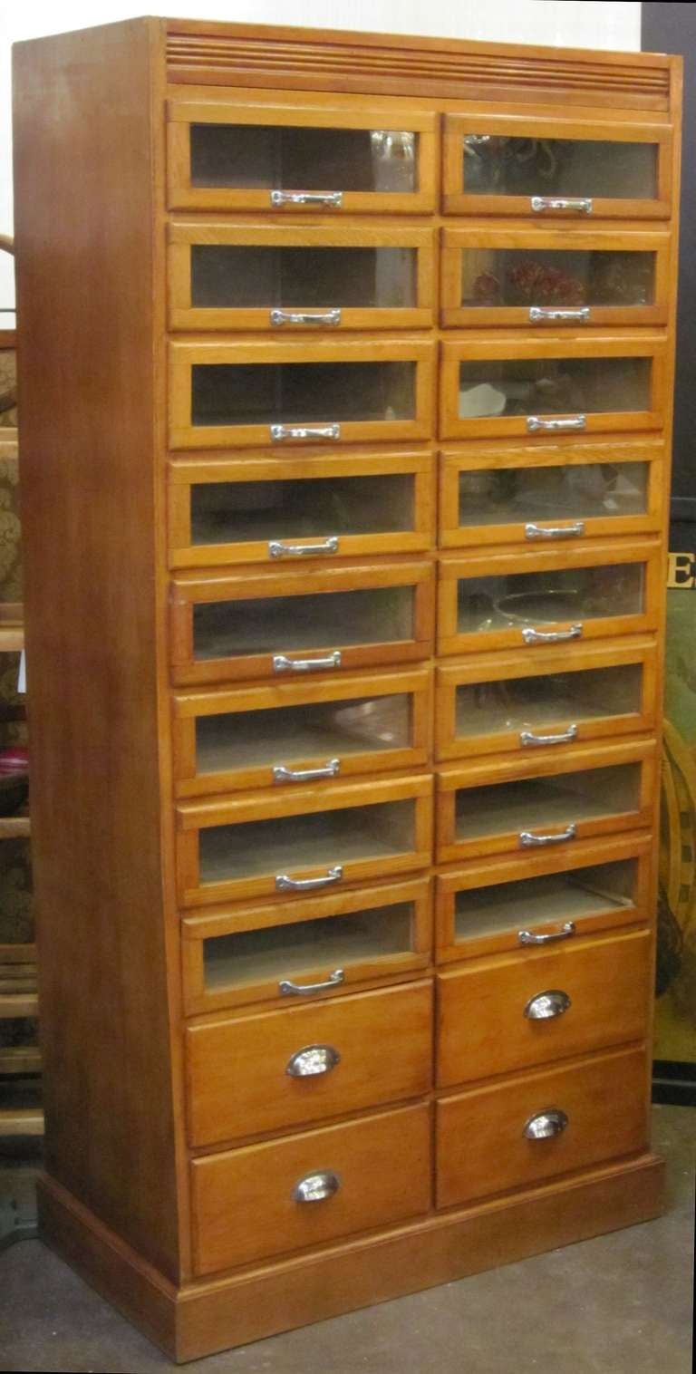 An exceptional haberdasher's or haberdashery cabinet from England featuring:

(16) glass-fronted drawers over (4) blind drawers - (20) drawers total.

Glass-front drawer inside dimensions:
Each drawer H 5