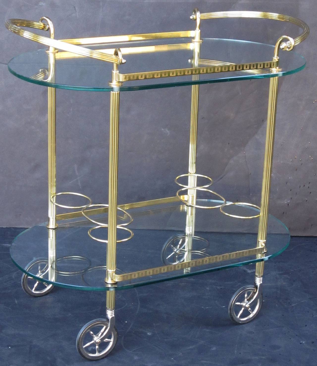 A vintage French oval drinks cart or serving trolley (bar cart) of brass and glass with etched rail galleries on two tiers, and bottle holders, on spoked rolling caster wheels. 

Perfect for use as a side or end table.