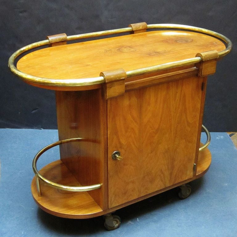 A handsome French drinks cart or cocktail trolley from the Art Deco era, featuring a figured burr walnut top and sides with rolled brass accents, enclosing cupboards on opposing sides, each with escutcheon and working lock (includes key).
The
