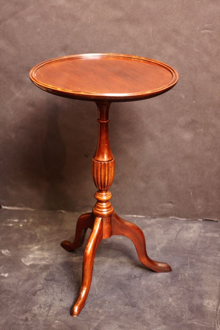 An English wine table of mahogany from the Edwardian-era, featuring a raised edge around the circumference of the round, moulded top, mounted upon a turned column pedestal with tripod base. Set upon pad feet. 

An excellent choice as a side table