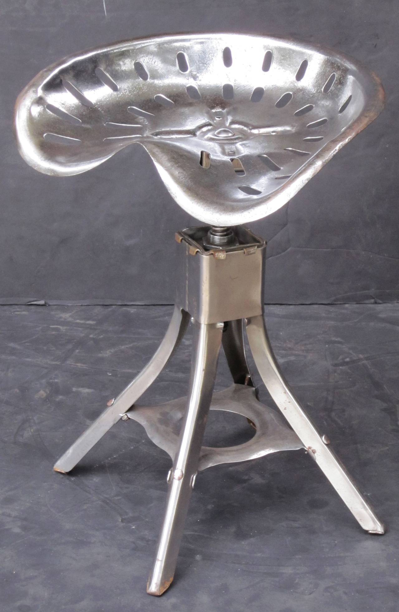 A handsome English tractor seat of polished steel, attached to a revolving four-legged stool stand.

The seat has adjustable height of 16