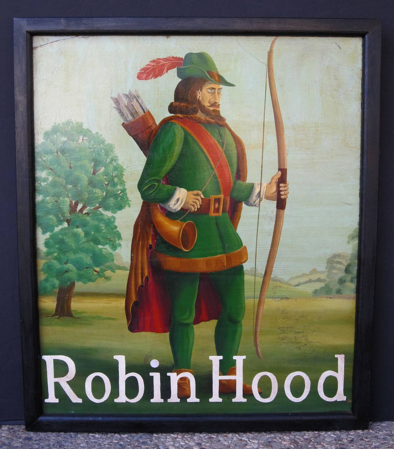 An authentic English pub sign (one-sided) featuring a painting of the legendary folk hero, Robin Hood, standing in a field with longbow in left hand, entitled: Robin Hood.

A very fine example of vintage advertising artwork, ready for display.