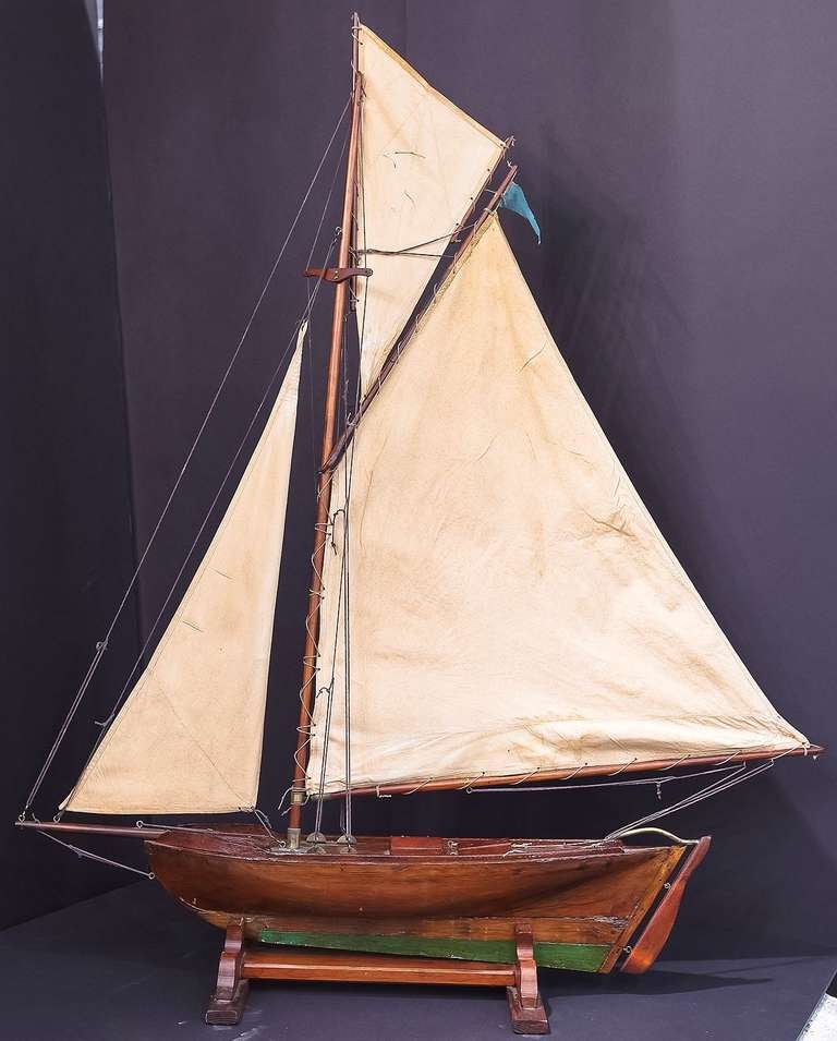 A handsome English pond yacht, handcrafted from wood and brass and featuring vintage cloth sails and fittings.
Displayed on a separate, custom-fitted stand.

An excellent gift for the nautical antiques collector. A wonderful display item for a