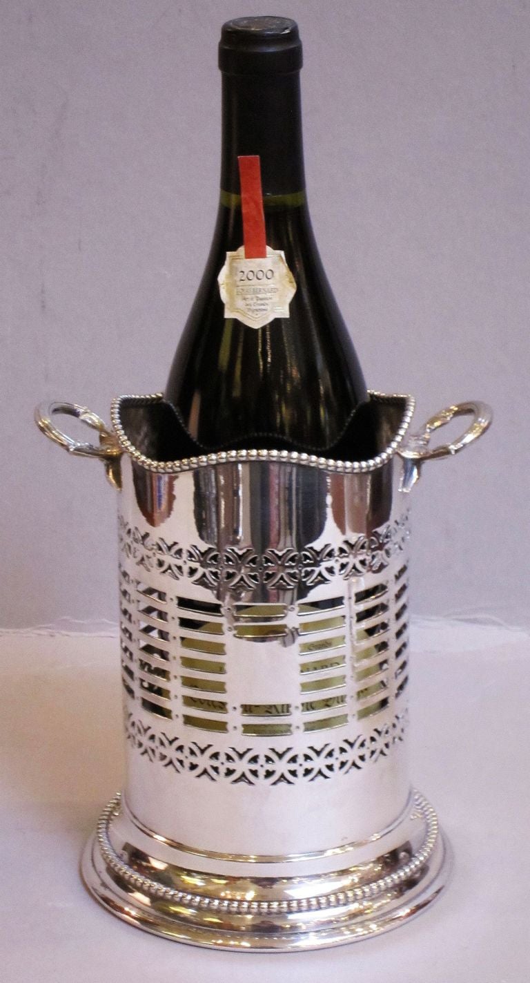 An English champagne or wine bottle holder (coaster) featuring a canister shape with an undulating rolled-edge top and a pierced design on the cylinder body.
Can be used as a soda siphon holder for the cocktail bar.

Dimensions:   
H 7 1/2