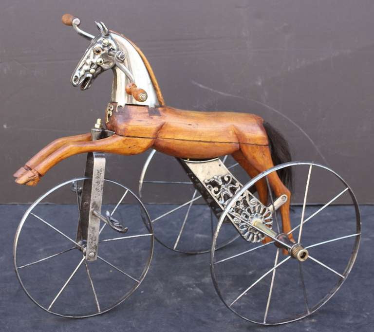 A 19th c. French velocipede or child's toy horse tricycle featuring a body of carved wood with brushed steel face-plate and glass eyes, resting on spoke wheels with brass accoutrements and horse-hair tail.
 
A handsome objet d'art similar to the
