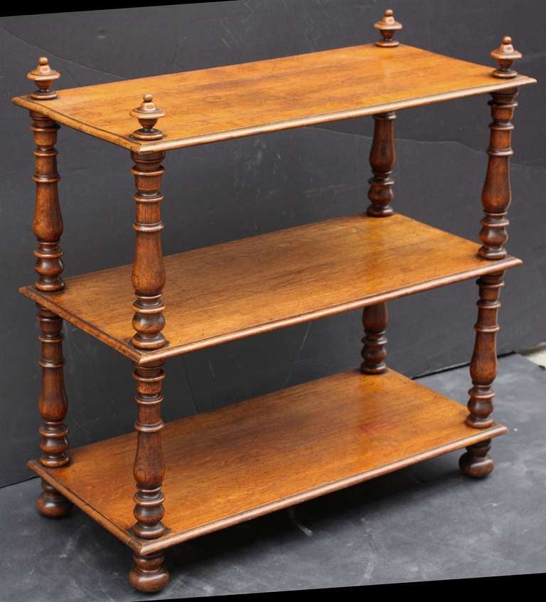 A large trolley server (or dumb waiter) of oak featuring three tiers with edge-moulded tops, each tier adjoined to four turned column supports topped with finials, set upon bun feet with rolling brass casters.
 
Such servers (often referred to as