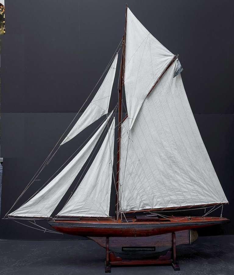 A handsome large English pond yacht, handcrafted from wood and brass and featuring vintage cloth sails and fittings. 

Displayed on a separate, custom-fitted stand. 

Dimensions: H 80 1/4