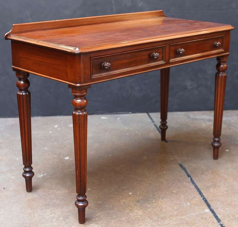 A handsome Scottish writing desk or side table of mahogany, featuring a moulded top with gallery back, over a frieze with two beaded short drawers, and standing on turned, reeded legs in the William IV style.

Bought by the owner in Edinburgh.