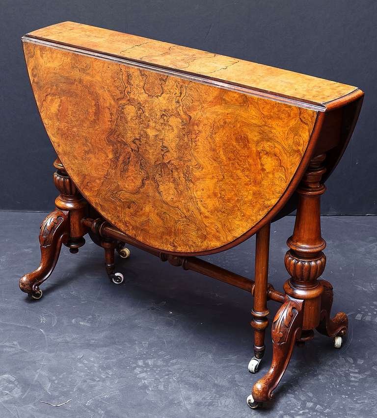 A handsome English drop-leaf table of walnut, known as a Sutherland table.
Featuring a moulded top of figured or burled walnut, with two drop leaves and turned gate-legs (with stretcher) that open to make a great tea or sofa table. On rolling