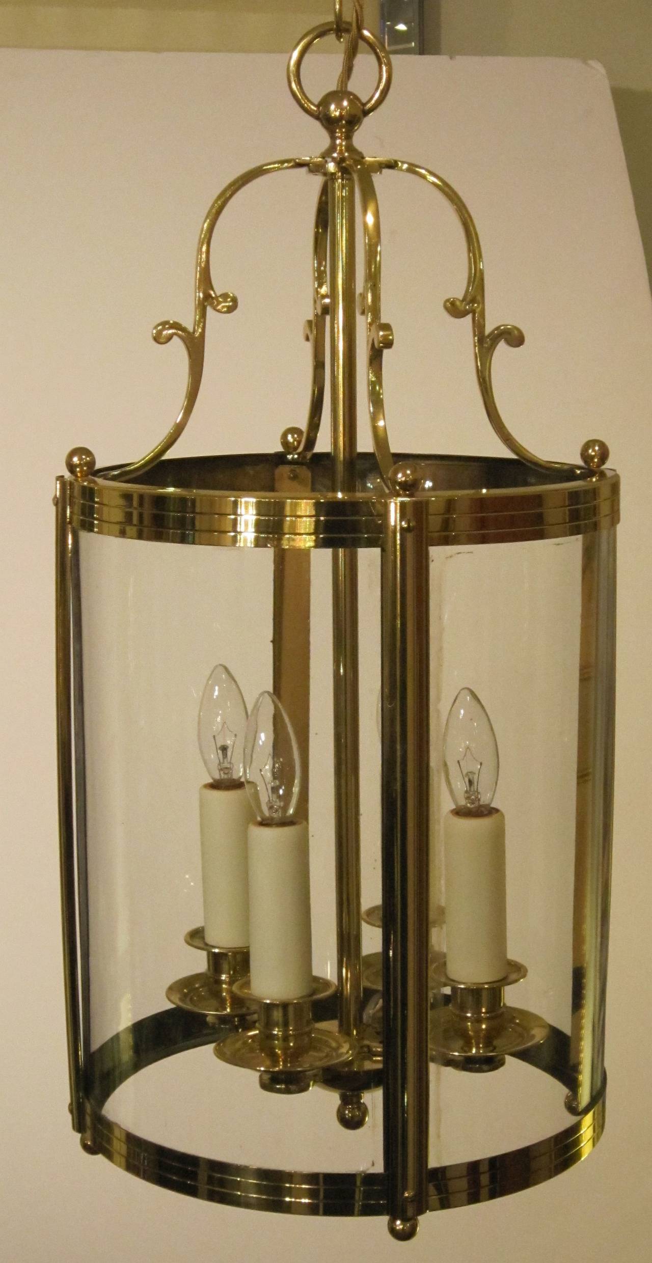A handsome French four-light hanging fixture or lantern of brass and glass featuring a cylindrical body with scroll-work top and four candle lights with brass bobeches. Decorative spherical finials to top and base. 

10 1/4