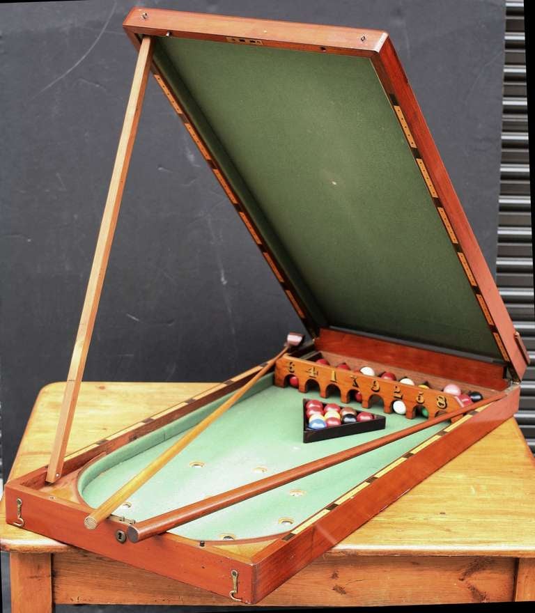 An English folding bagatelle (or gaming) table of mahogany featuring a felt interior with balls, cue, and mace and scoring holes down the sides.

Bagatelle (from the Château de Bagatelle) is a billiards-derived indoor table game (similar to pool),