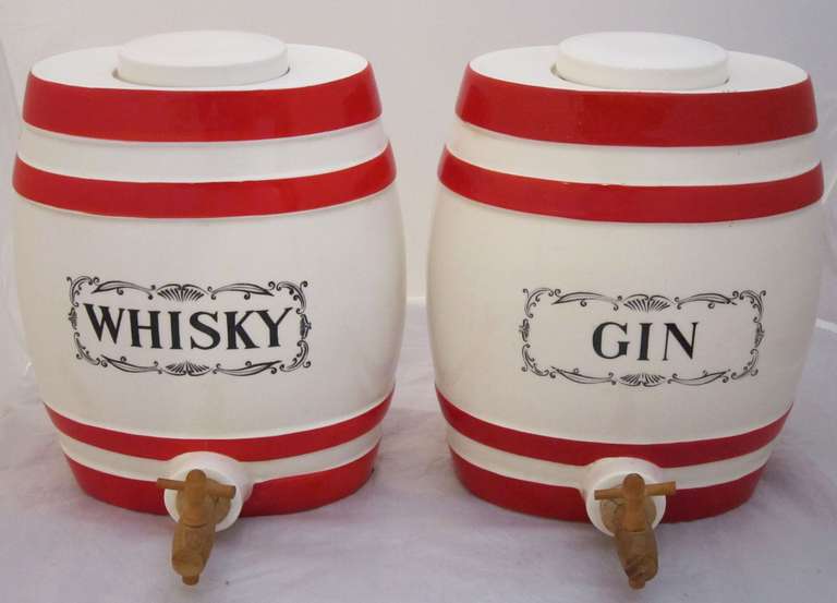 A handsome pair of Scottish large spirit decanters modeled as ceramic barrels, each featuring a lidded top (with removable lid), barrel body with raised red stripes on top and bottom, transfer logo of Whisky (Scottish spelling of whiskey) or Gin,