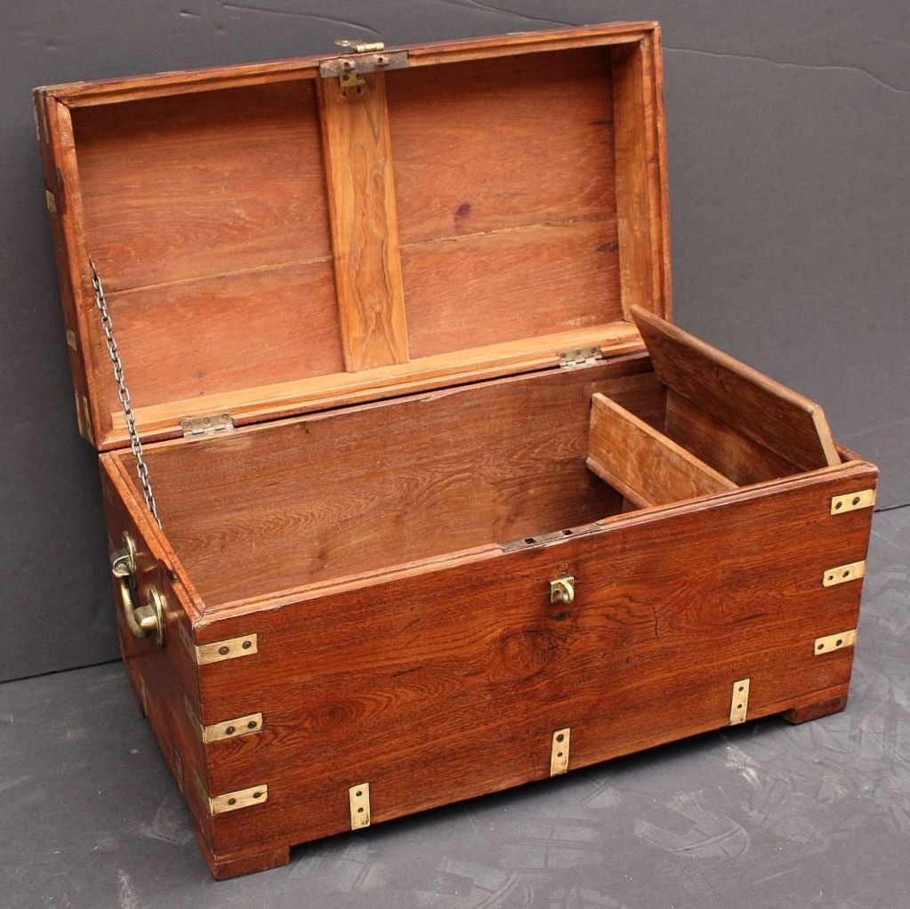 A handsome English Military Officer's Campaign-era trunk of teak featuring hand-cut brass binding and hardware and resting on raised feet.<br />
<br />
Campaign-era trunks and coffers were the travel items of British military officers who bought