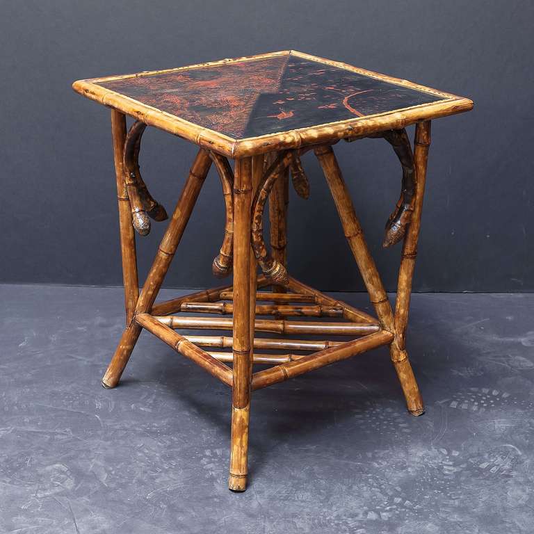 A handsome English bamboo square occasional or side table, featuring a lacquered panel top with Asian design over a frame support of turned bamboo.