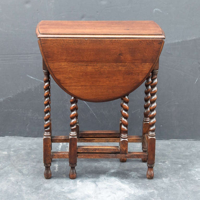 A classic English drop-leaf gate-leg table of oak, featuring a moulded top with drop-down sides, over a joined stretcher of eight barley-twist supports. Opening to an oval top.

Condition: Excellent

Specifications: Height: 28.5, Width: 23.5,