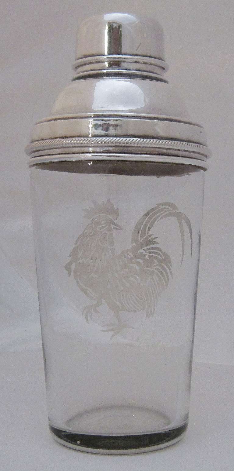 A vintage English cocktail drinks shaker of glass with removable silver cap, featuring an etched cockerel on the cylindrical body.

Perfect for the bar.